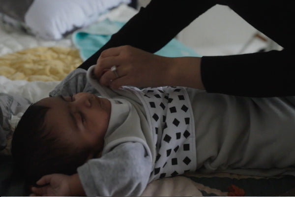 Parent dressing baby in layers before sleep 