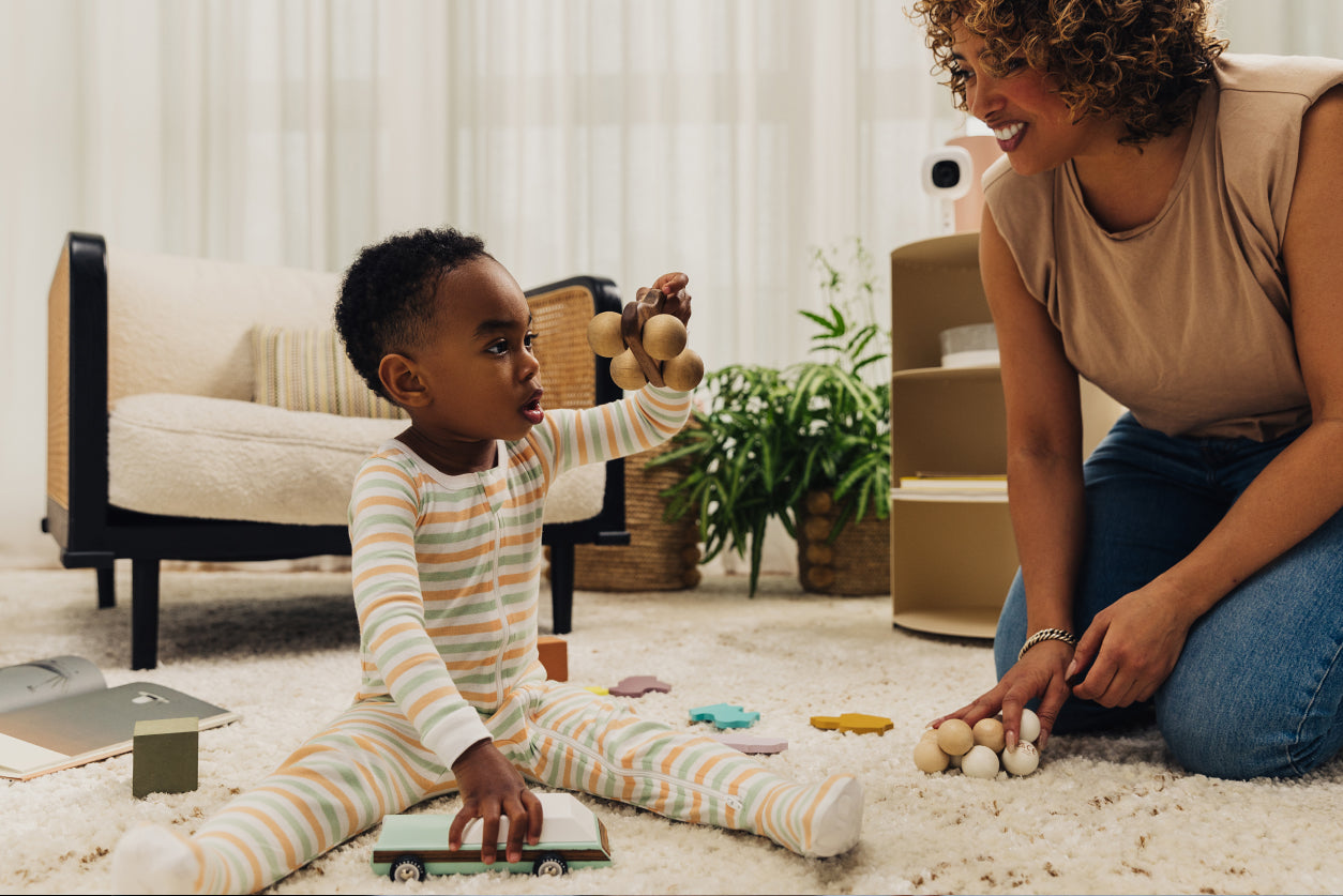 Mom and Son playing with nanit baby monitor on flex stand in the background