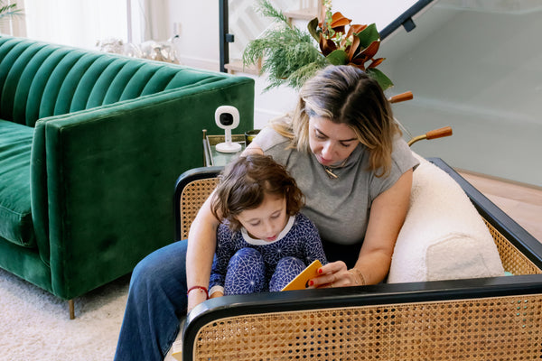 Mother and daughter reading during holiday season with nanit pro baby monitor and flex stand in the background