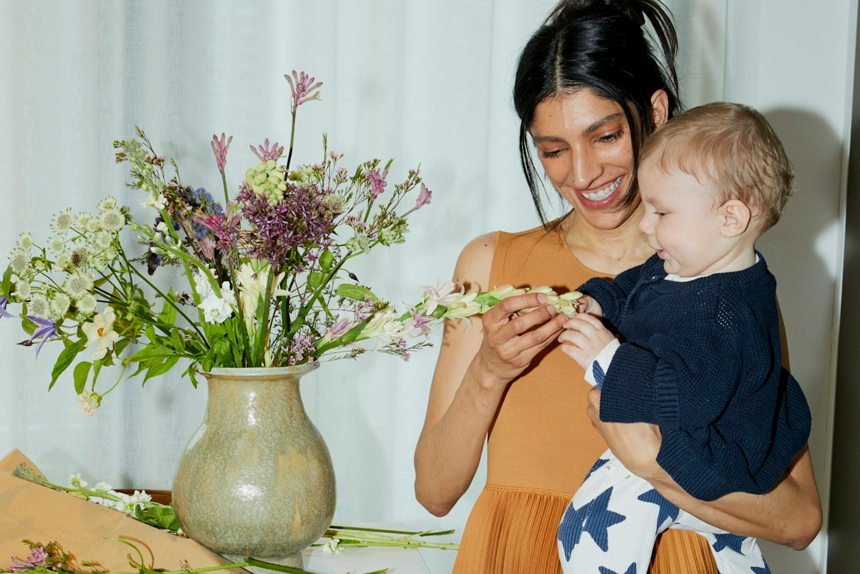 New Mom Gift Guide | New mom with baby playing with flowers