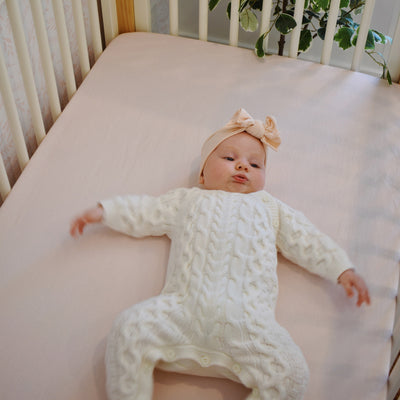 zoomed in on baby laying in crib on top of botana hemp crib sheet in rosewater 