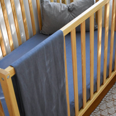 botana hemp crib sheet in night swim on crib with pillow on top and blanket hanging on crib 