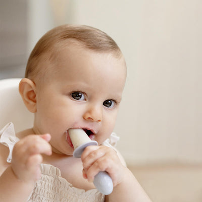 baby holding and biting on tiny pops 