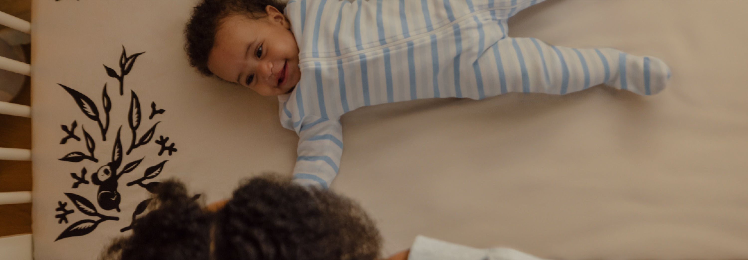 baby smiling at mom while laying on crib