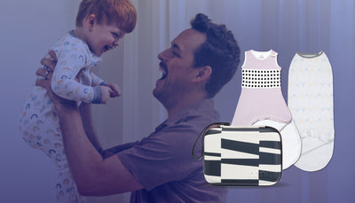 dad smiling and holding toddler with showing breathing wear sleeping bag, sleep wear swaddle, and travel case