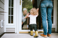 Grandma greeting toddler at the door with mom