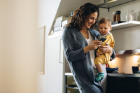 Mom holding baby while looking at her mobile