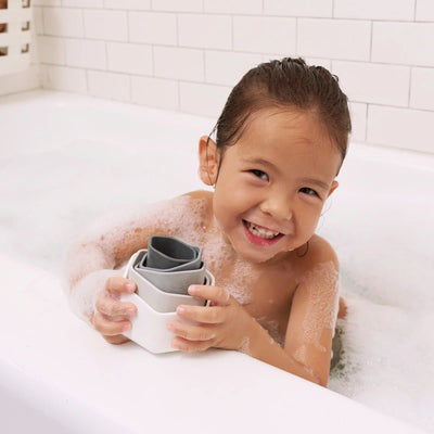 toddler playing with lalo stacking cups in bathtub