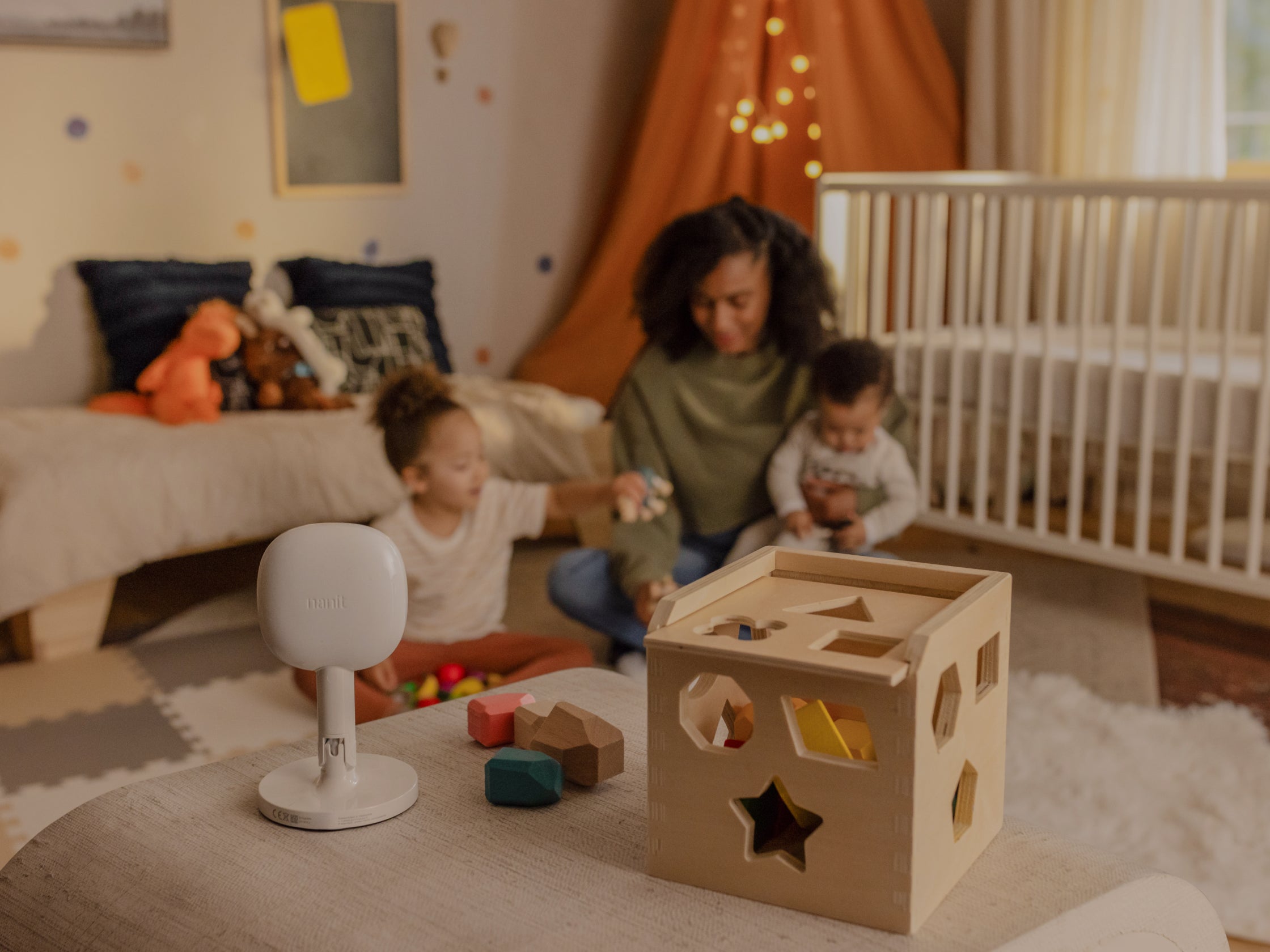 nanit pro camera + flex stand on top of shelf facing towards mom and kids with playing cubes next to pro camera