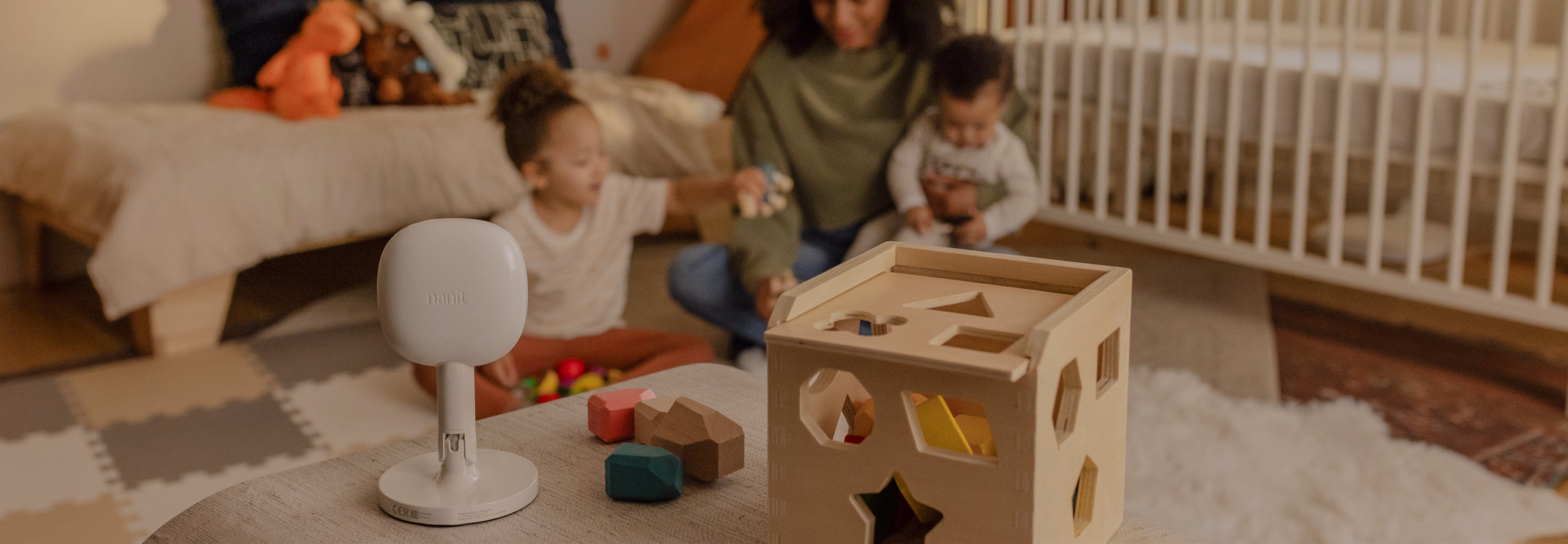 nanit pro camera + flex stand on top of shelf facing towards mom and kids with playing cubes next to pro camera