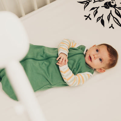 baby laying in crib with nanit sleep wear sleeping bag in spruce green